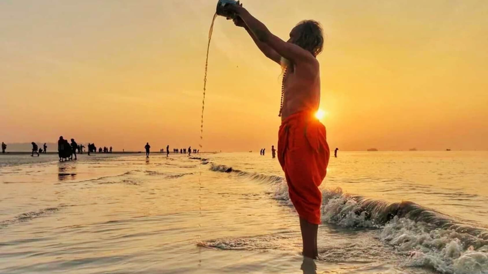 <p>A pilgrim pours sacred water into the sea at sunrise. (Picture courtesy Government website)</p>