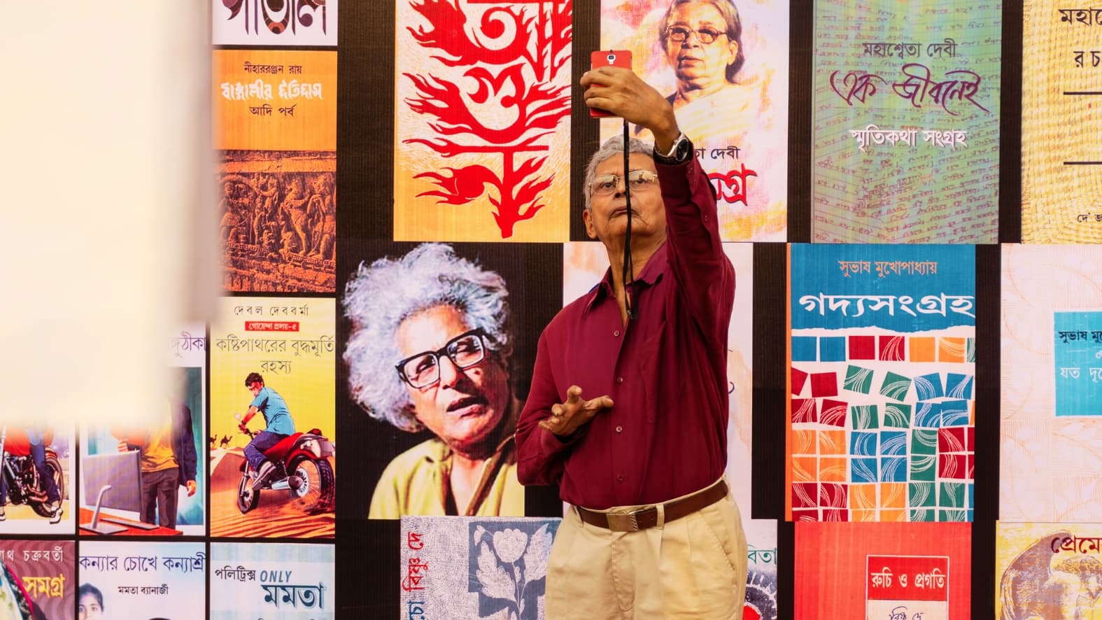 <p>A visitor takes a "selfie" with a vibrant display of Bengali book covers. (Shutterstock)</p>
